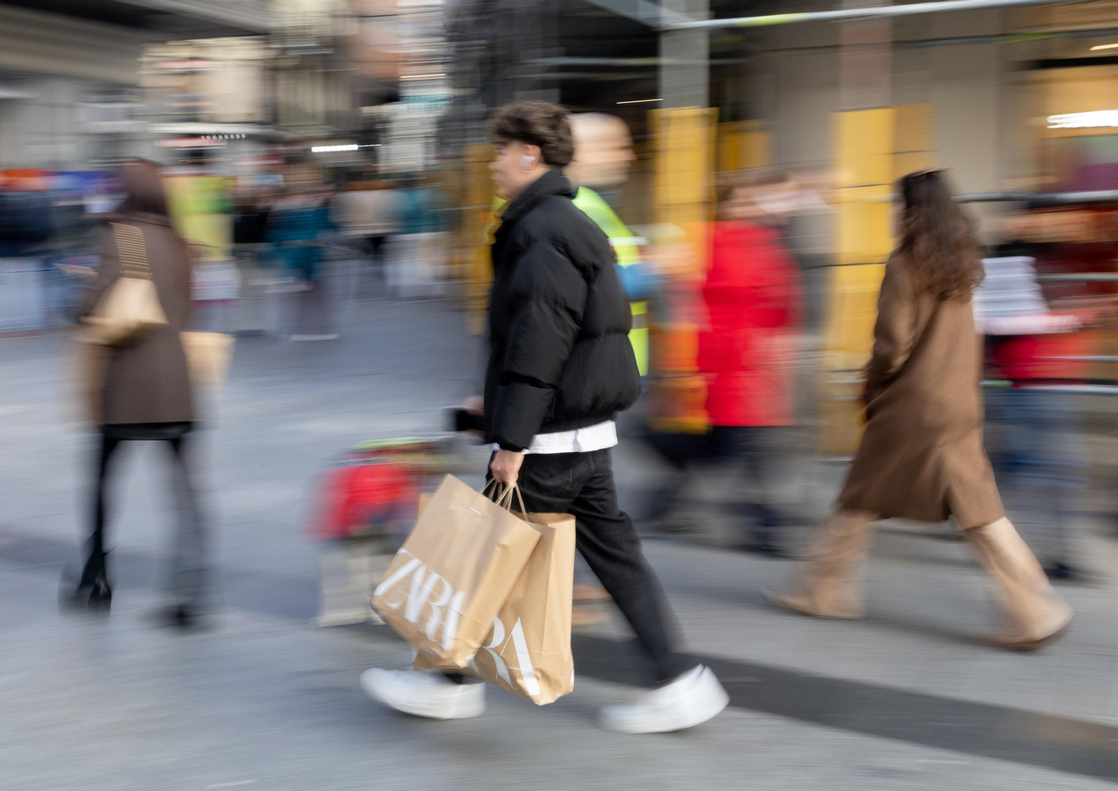 Archivo - Varias personas con bolsas tras comprar en distintos comercios